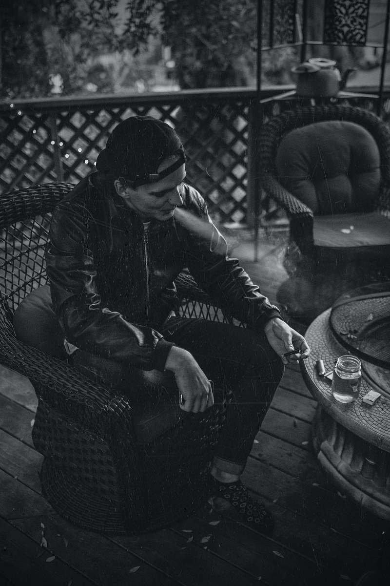 furniture greyscale photography of man sitting on the chair smoking chair