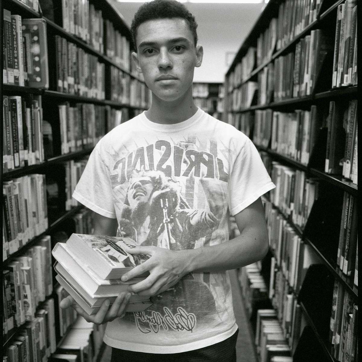 indoors man in white crew neck t-shirt holding book room