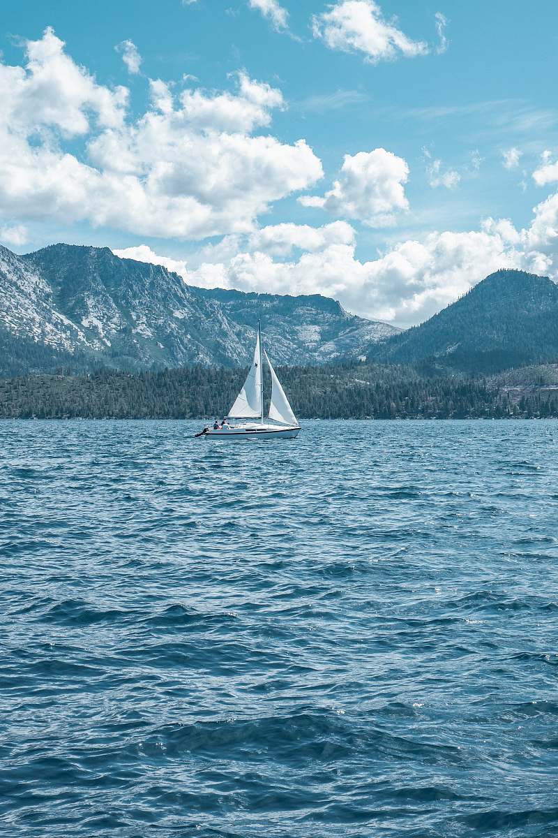 transportation white sailboat on sea near mountain under white clouds and blue sky during daytime vehicle