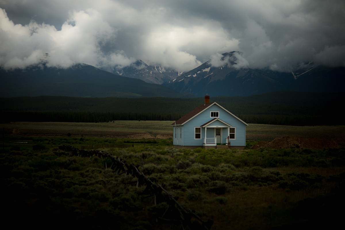 house house on grass field under gray sky cottage