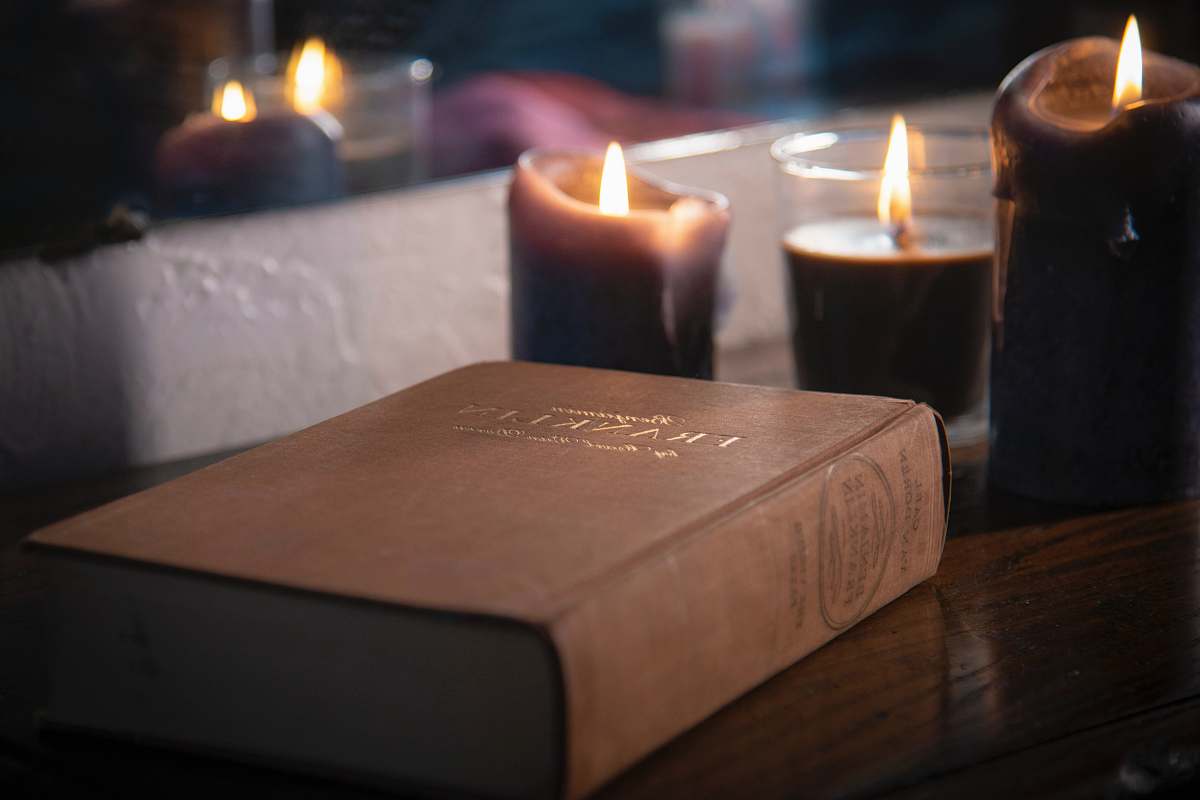 fire brown hardbound book near lighted pillar candles laurelton
