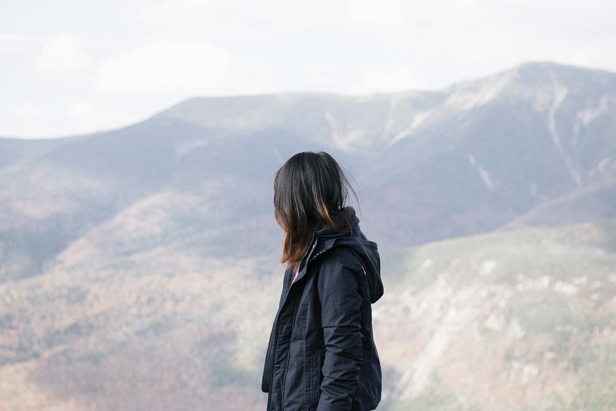 jacket person wearing black jacket leaning mountain during daytime apparel
