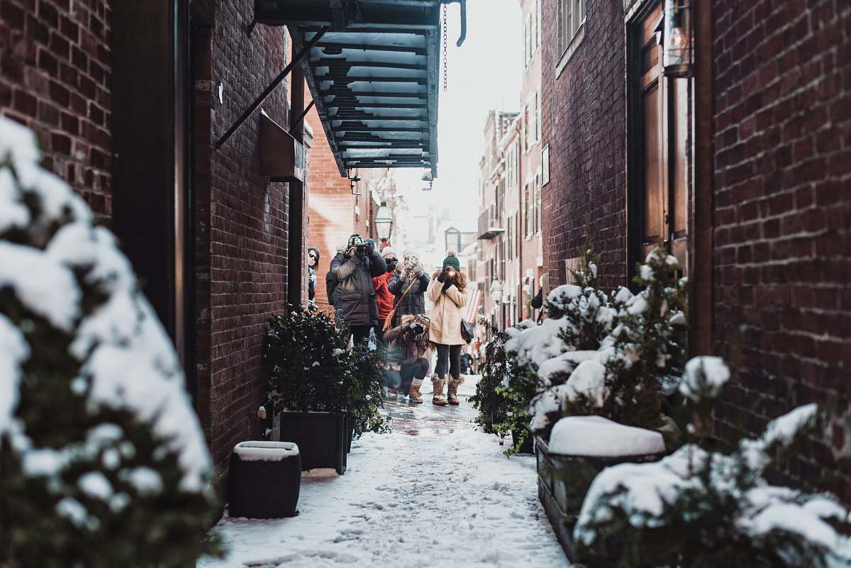 plant girl standing in between buildings surrounded by plants covered with snow snow