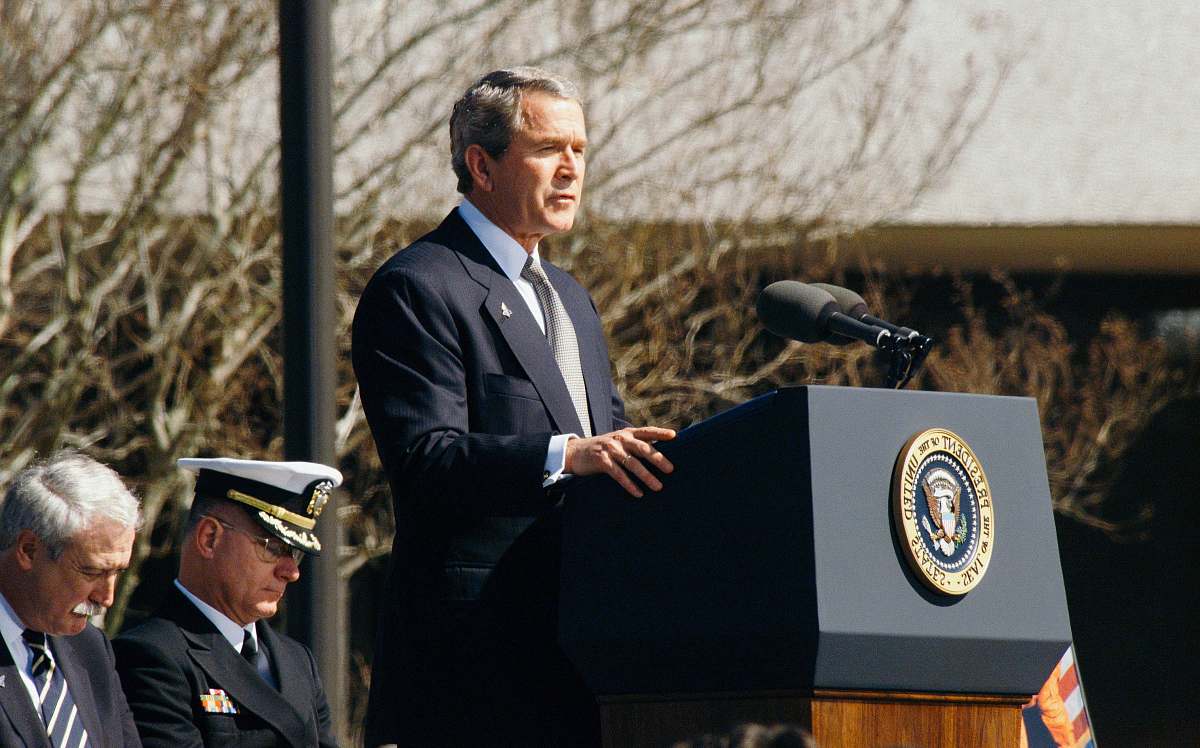 person George W. Bush standing on lectern during daytime speech