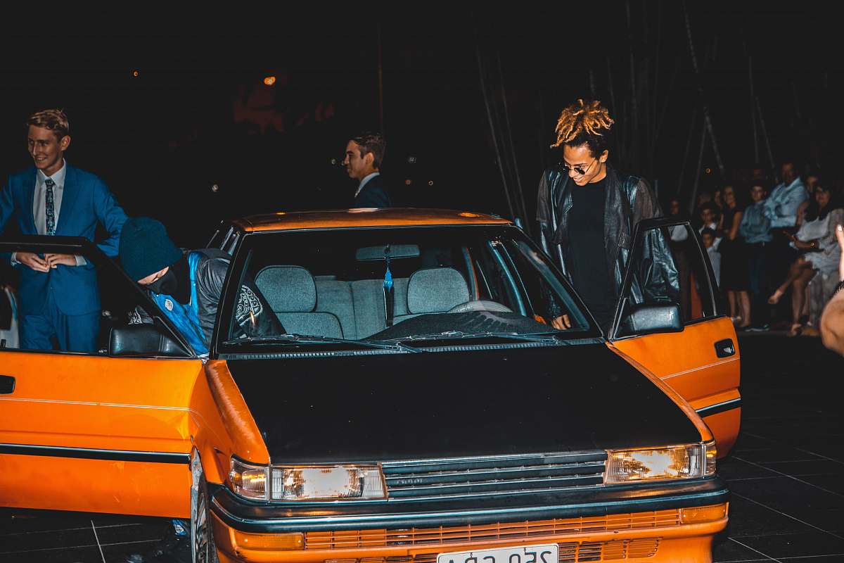 person group of men riding on orange and black sedan people