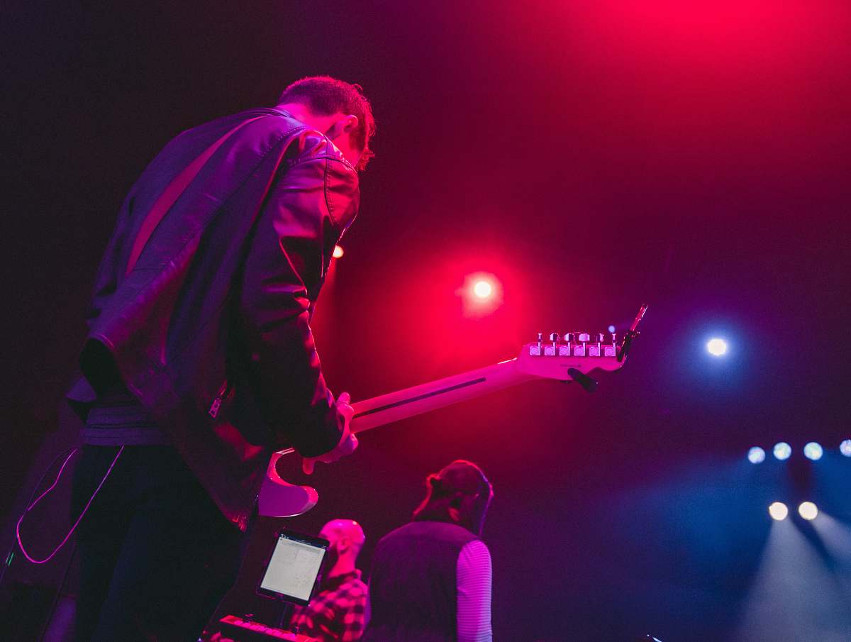 person man playing guitar on stage lighting