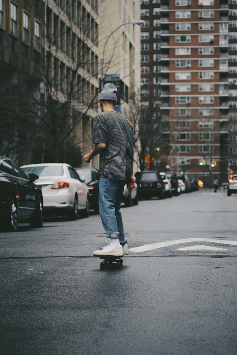 person man riding skateboard near high rise building people