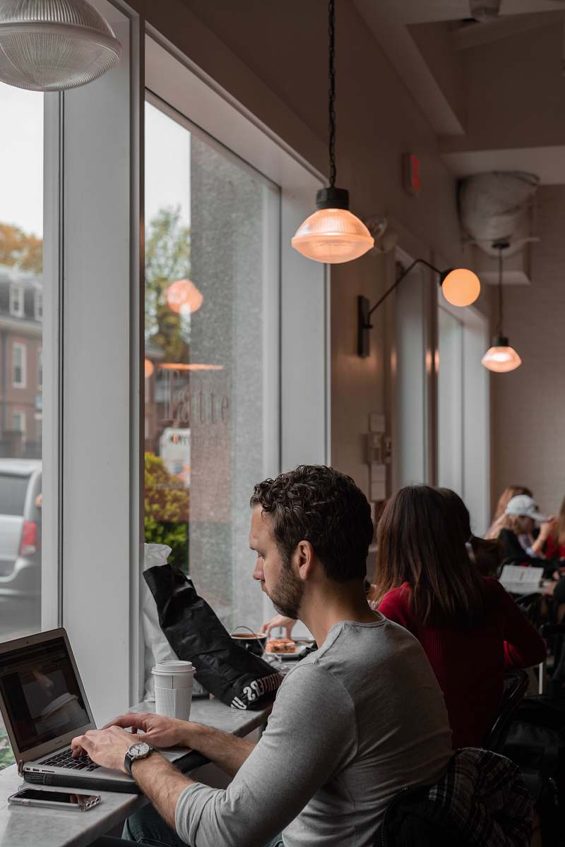 person man sitting and using laptop inside building sitting