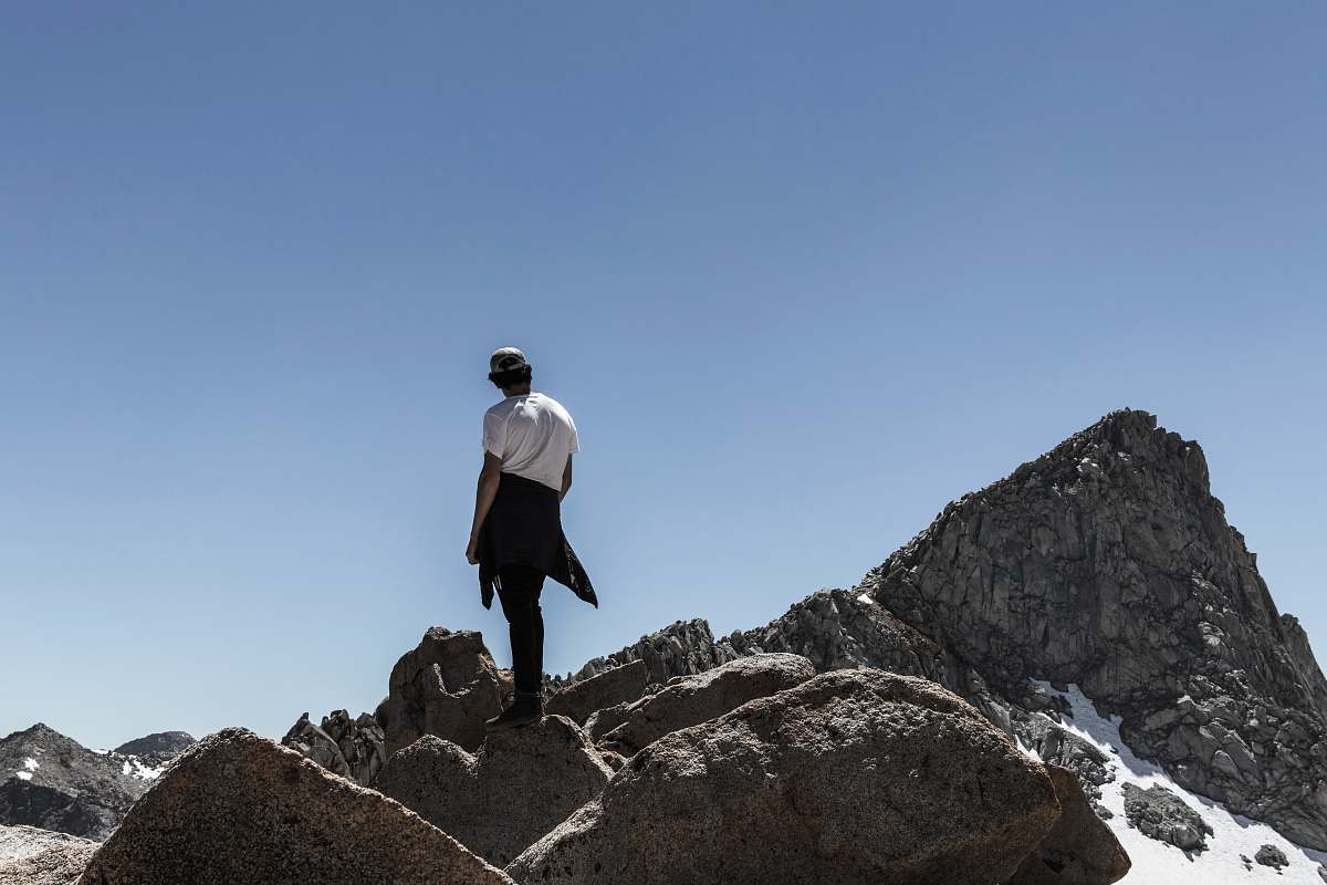 person man standing on rock mountain peak people