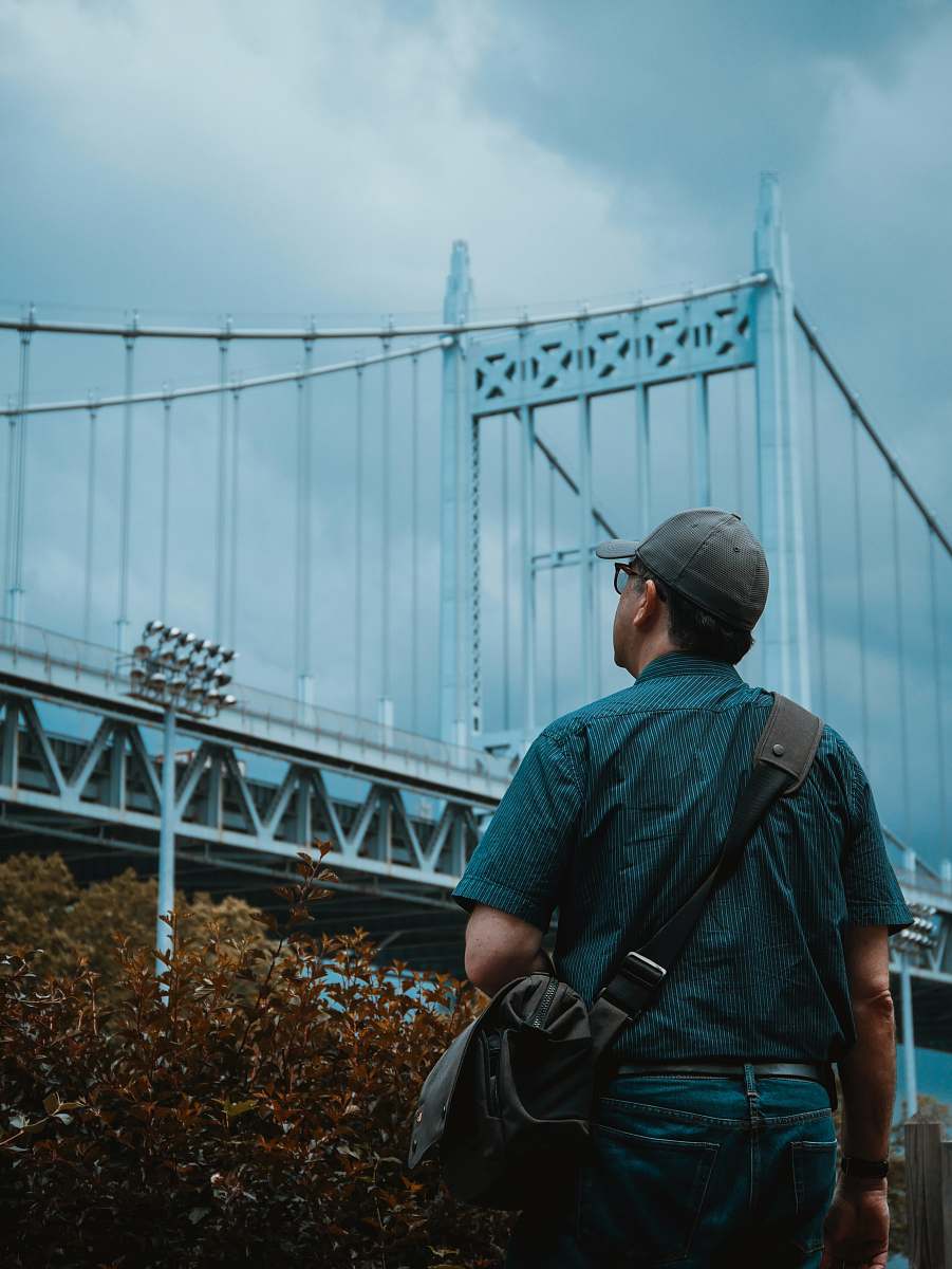 person person standing and looking at gray metal bridge people