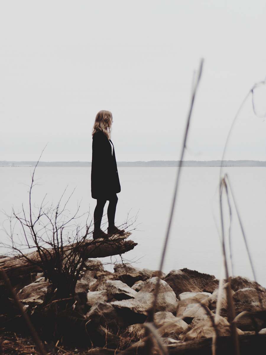 person woman in black coat standing on log wood