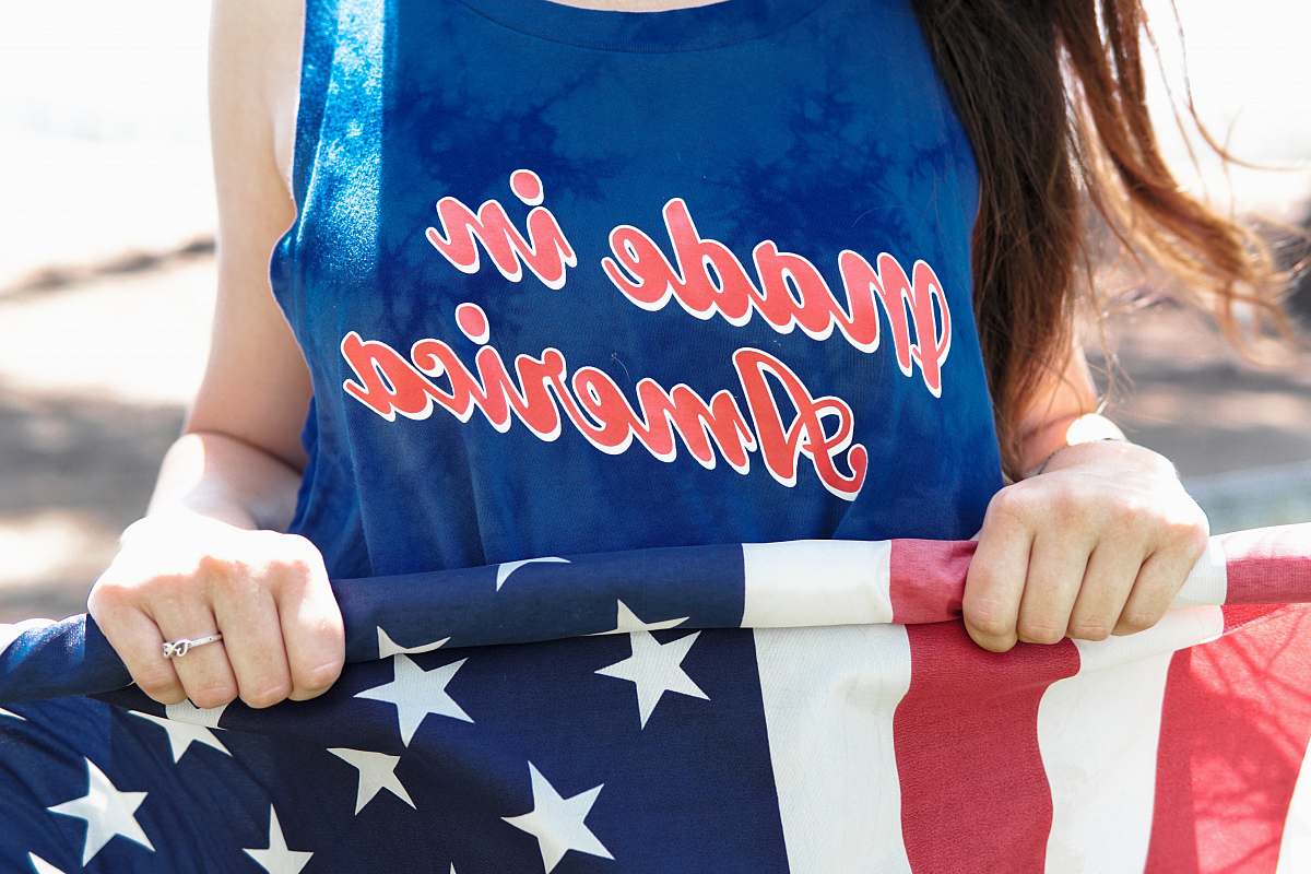 people woman in blue sleeveless top holding flag of America person