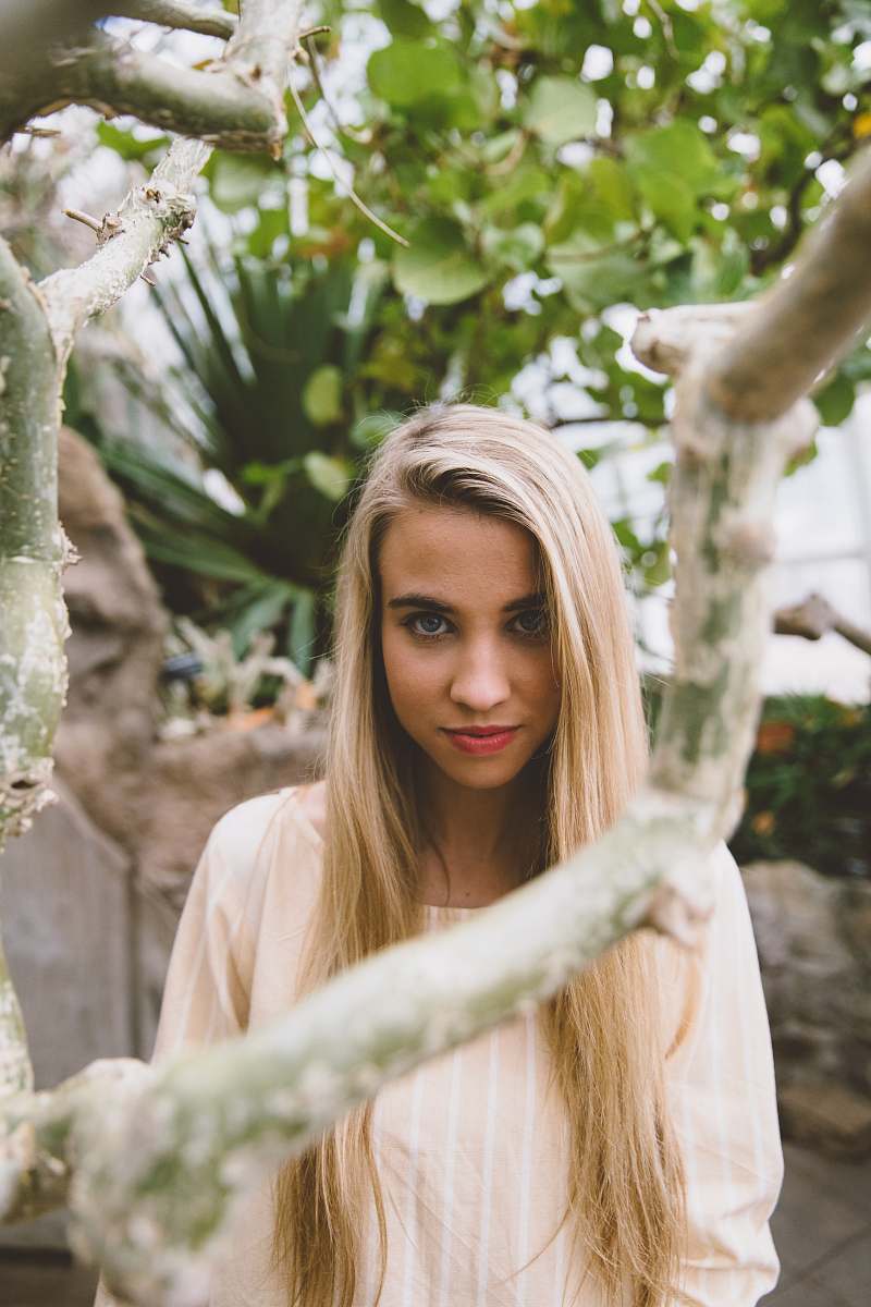 people woman wearing peach-colored scoop-neck top standing near green leafed tree person