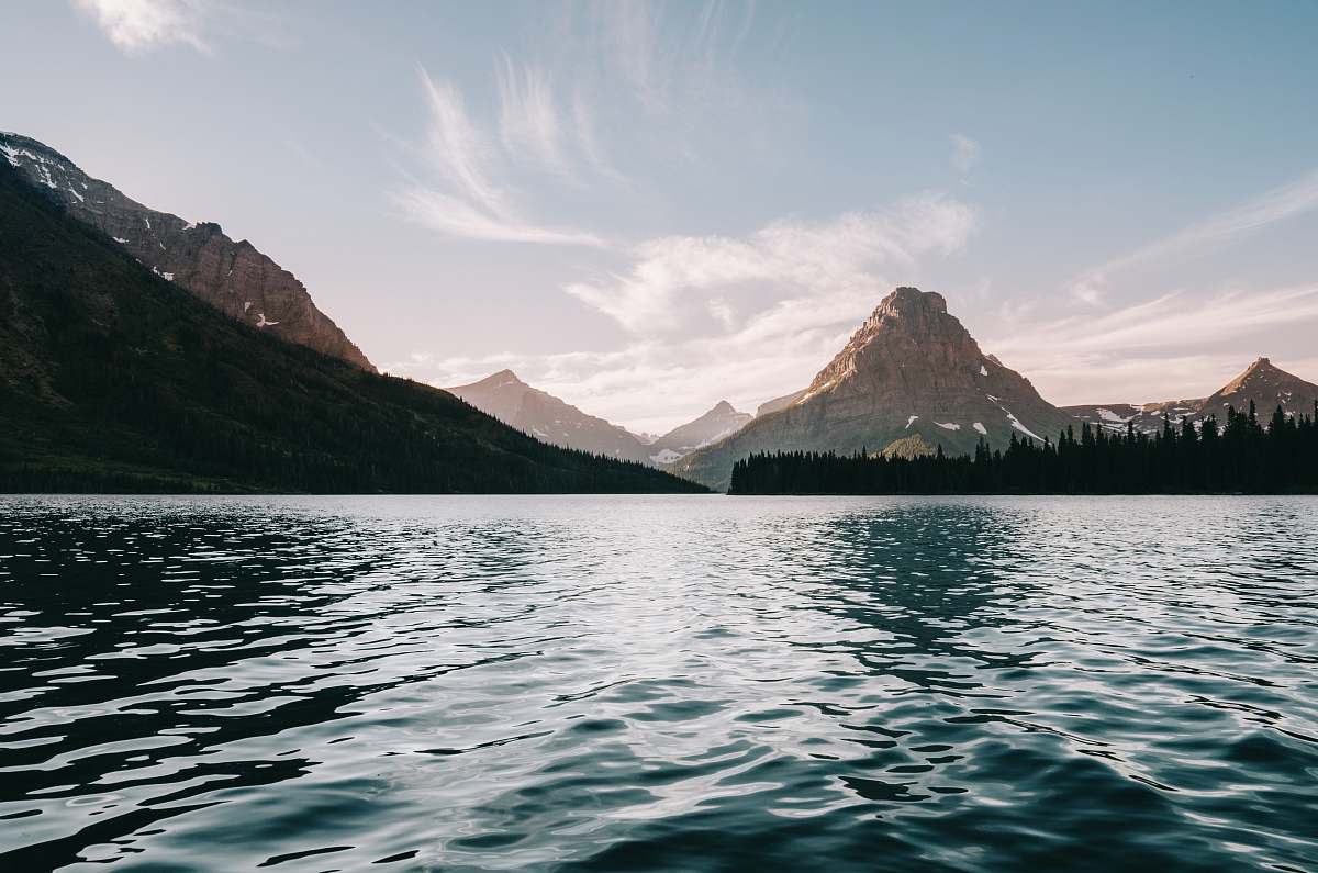 grey body of water near body trees and mountain nature