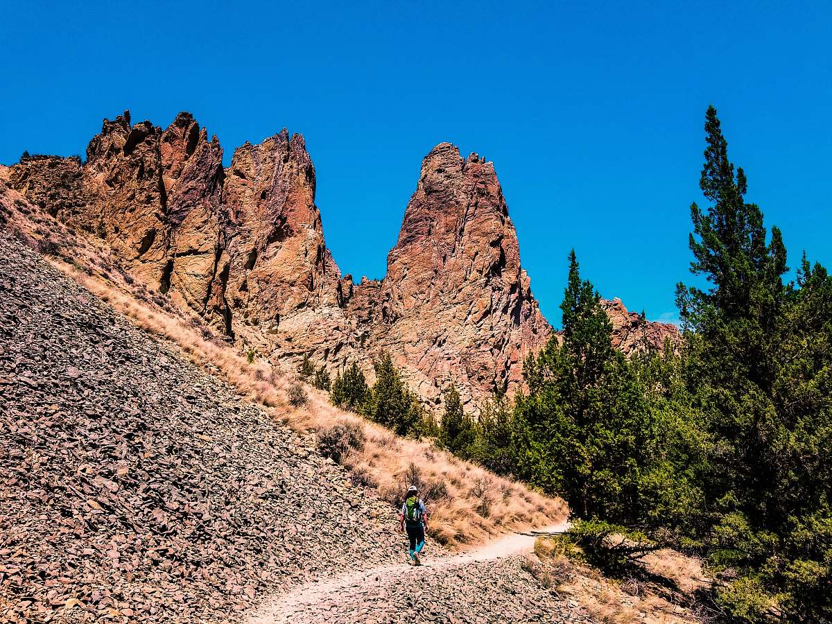 rock man walking on mountain pathway under clear sky smith rock state park