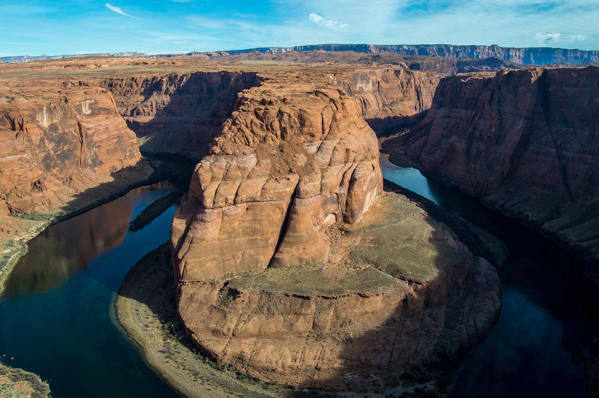 outdoors aerial photography of brown and green mountain surrounded by body of water during daytime mountain