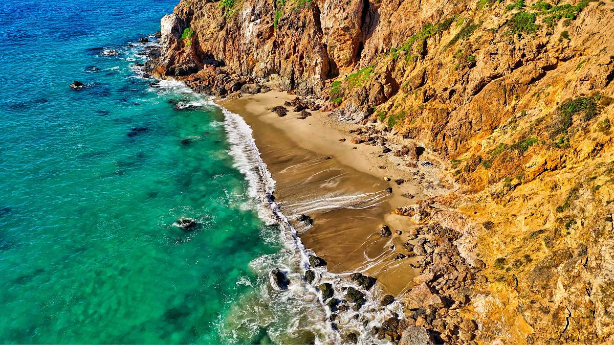 shoreline aerial photography of rock formation beside body of water water