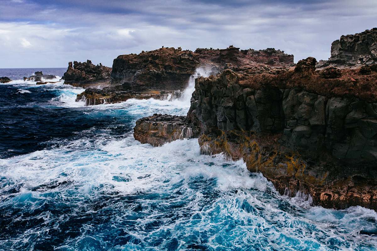 water body of water crashing on brown rocks and cliff sea