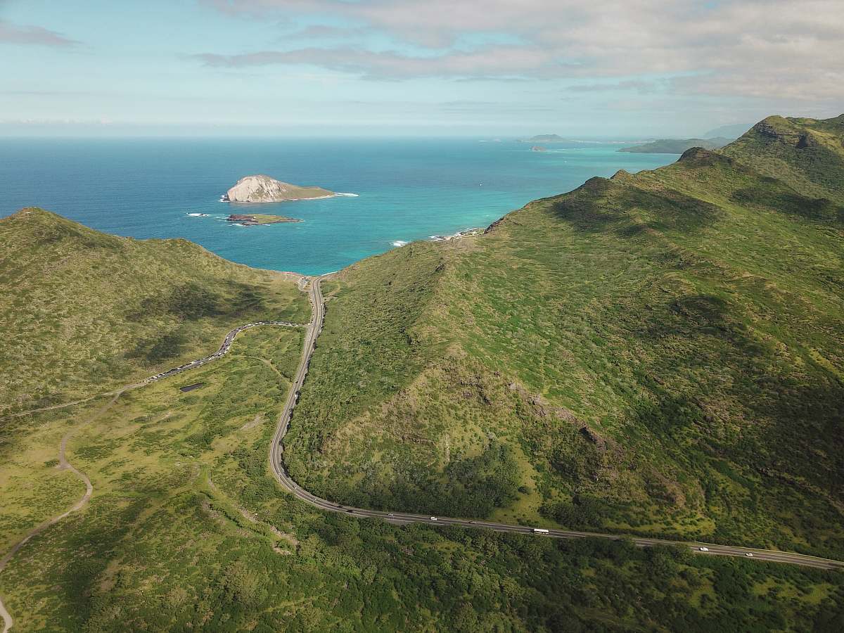 sea aerial photograph of mountain besides body of water water