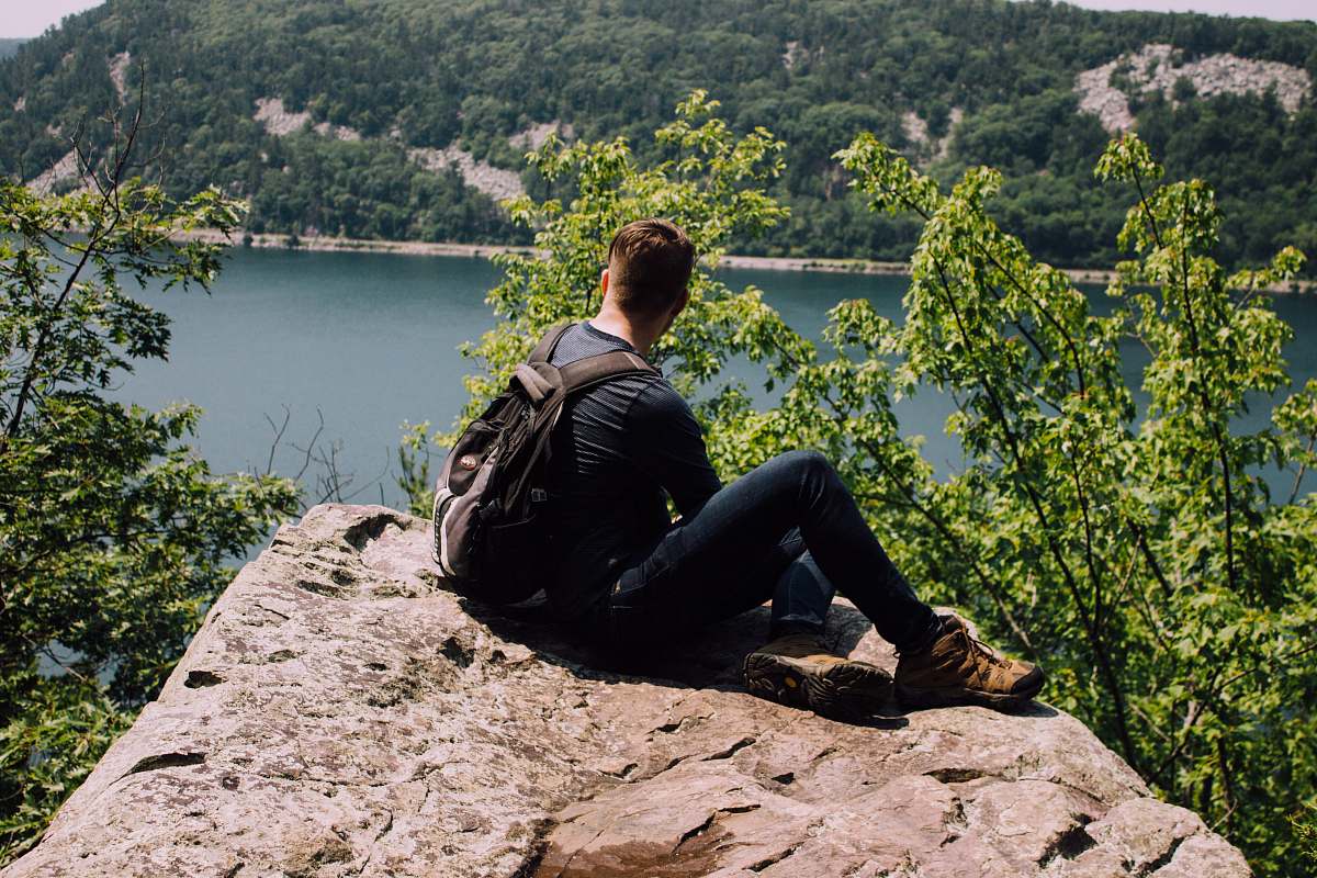 person person with backpack sitting on gray rock human
