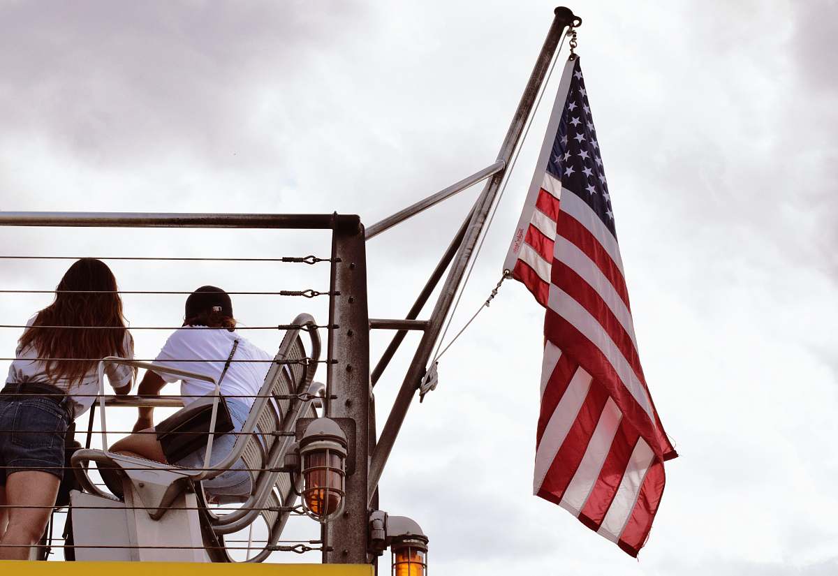 flag man in black jacket sitting on chair near us flag during daytime symbol