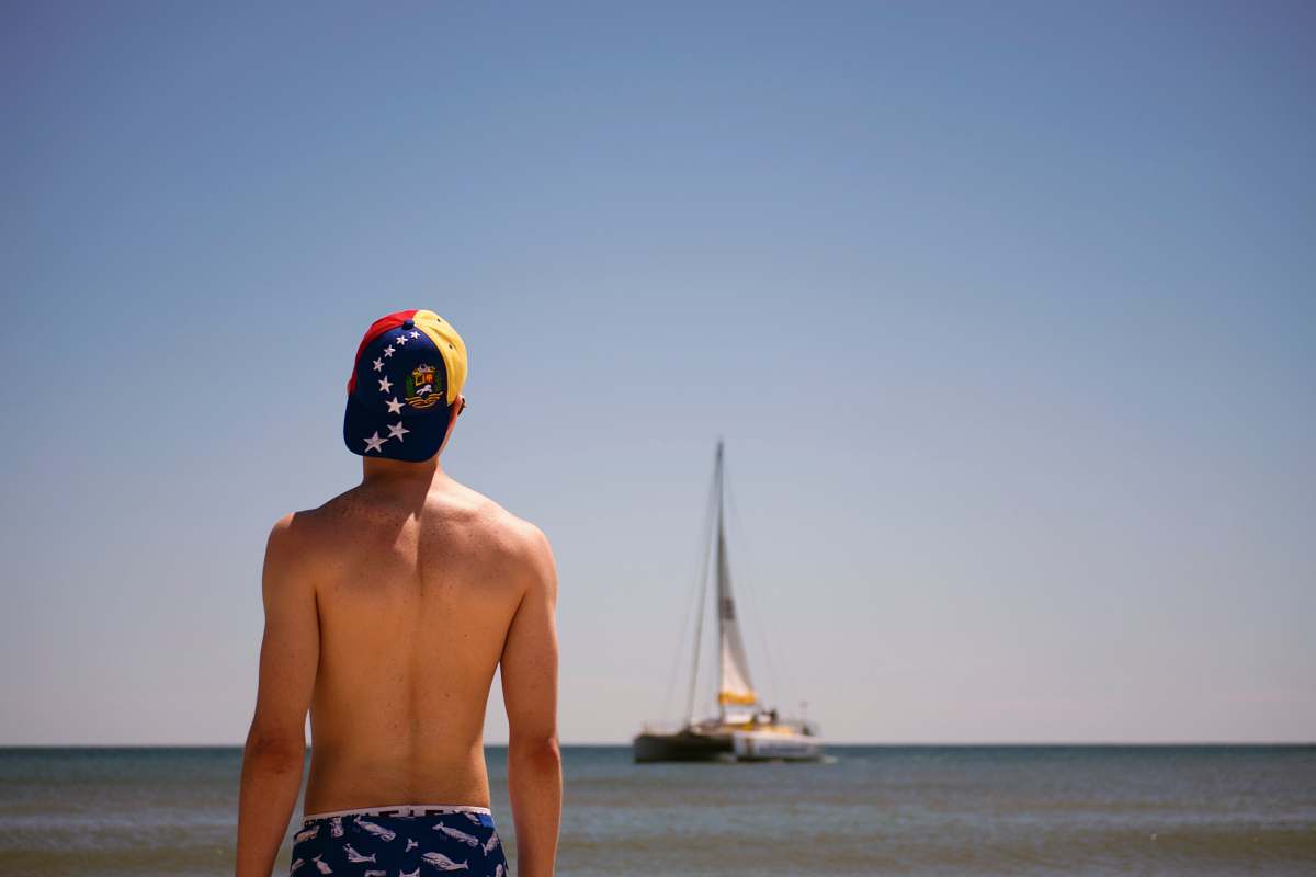 human man standing facing boat during daytime sailboat