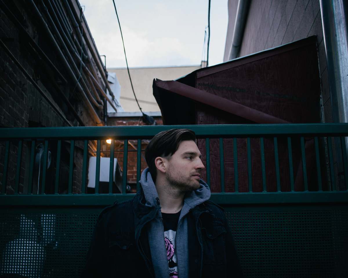 human man wearing gray and black pullover hoodie beside green metal gate people