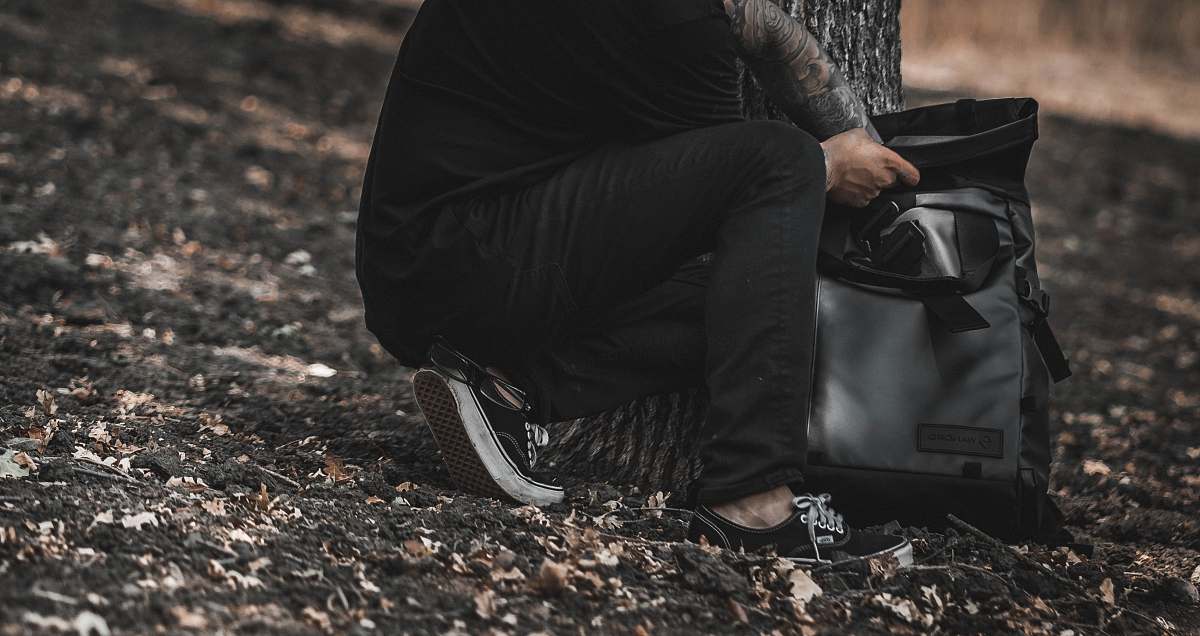 human person holding gray and black backpack people
