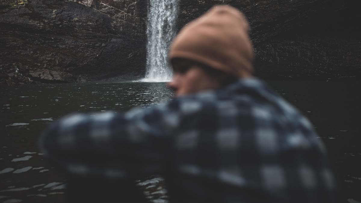 human person sitting beside waterfalls people