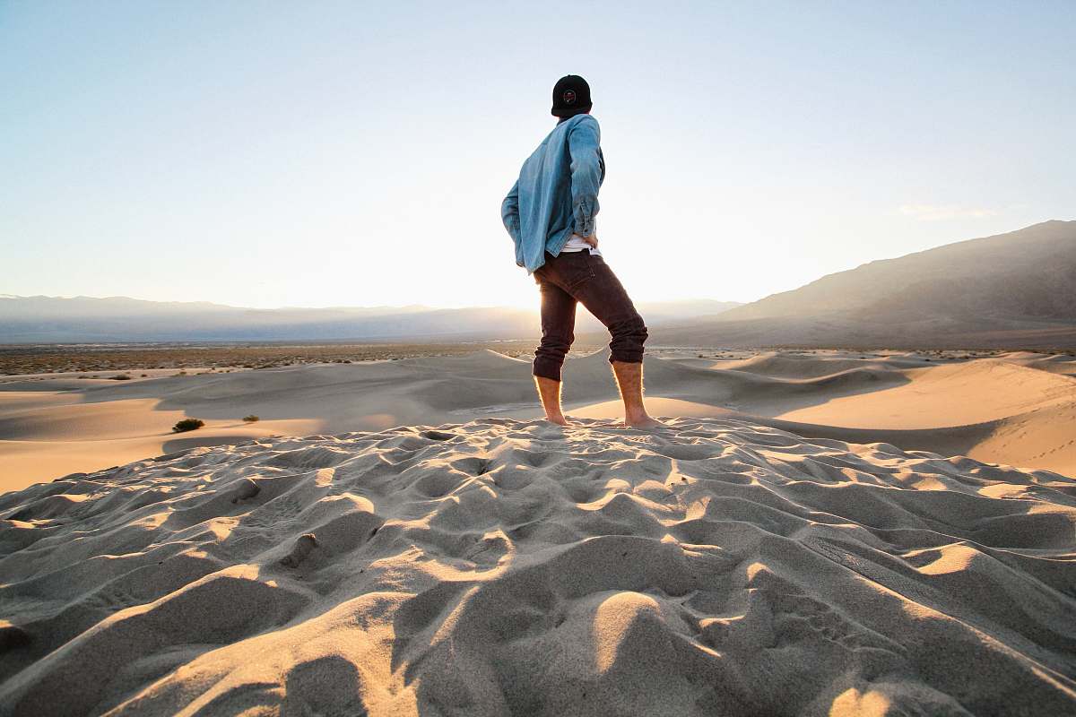 people person standing at sand wearing black pants and teal jacket human