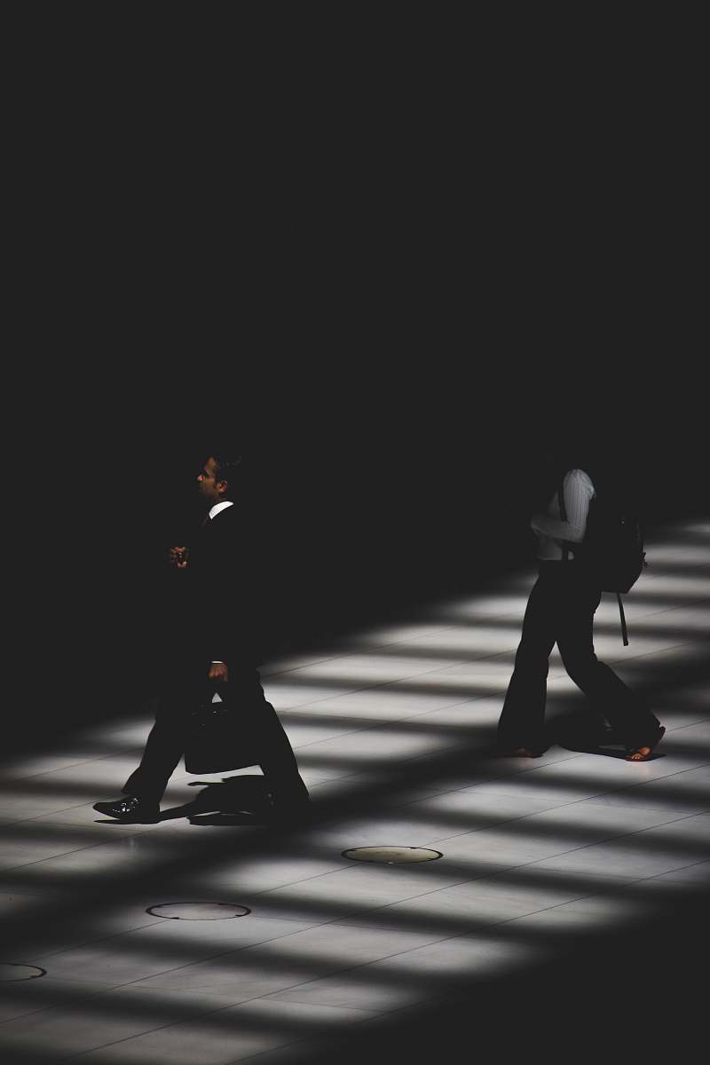 black-and-white two person walking inside building with black lighting people