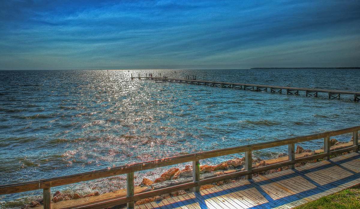 banister blue sea under blue sky handrail