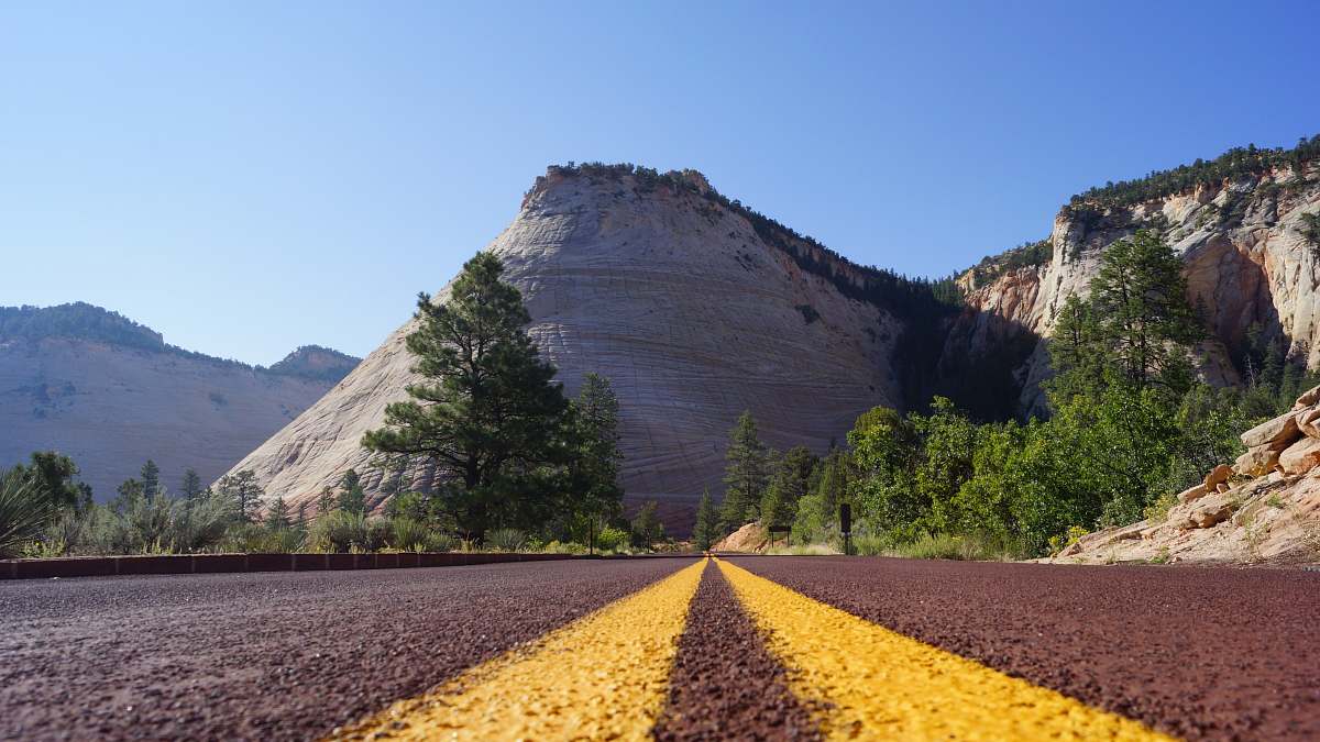 gravel road near trees and mountains dirt road