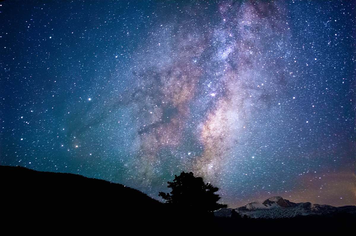 night silhouette of trees and mountain under blue sky at nighttime astronomy