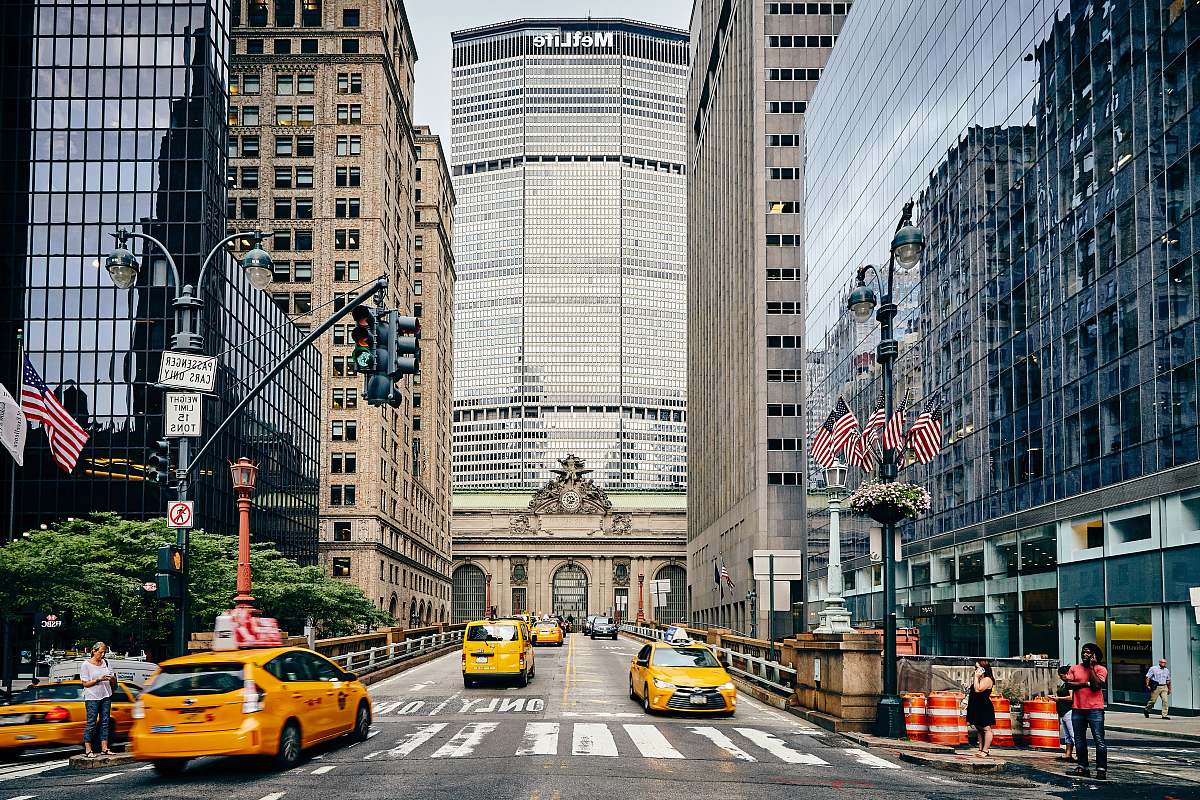cab people and cars on street near high rise buildings during daytime automobile