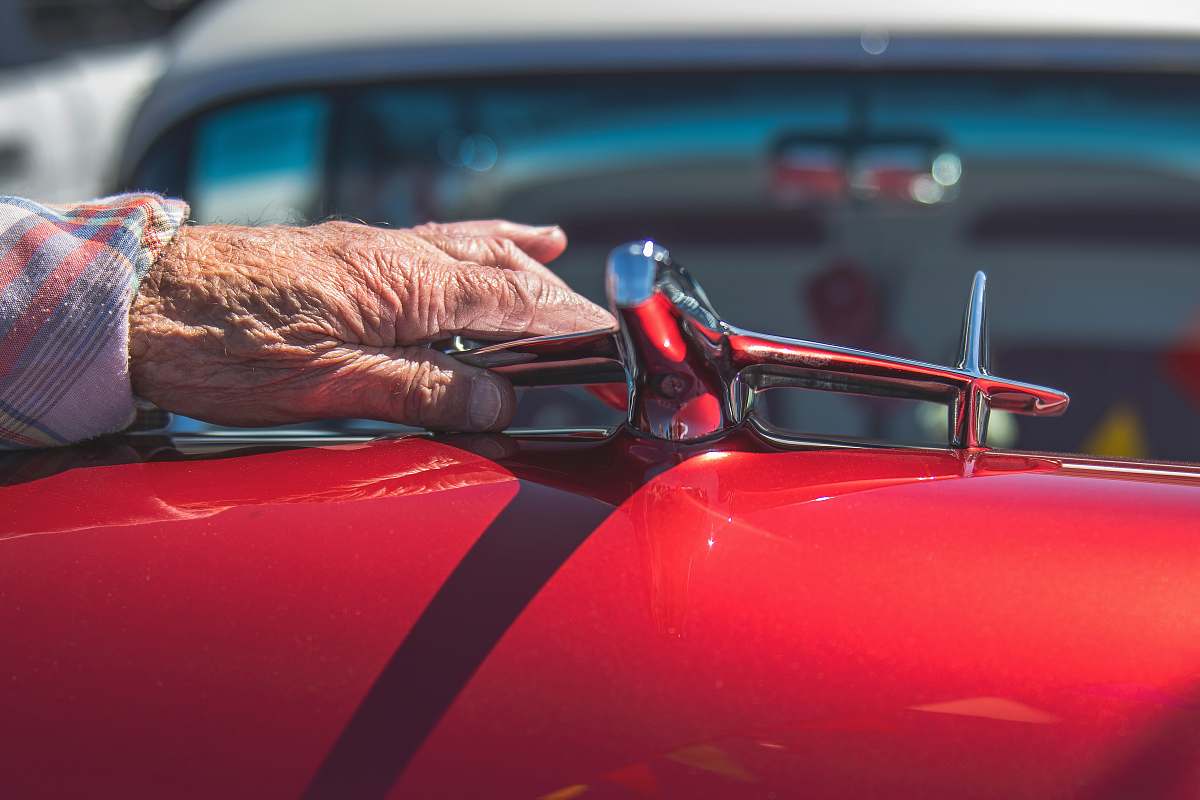 car person touching chrome-colored emblem automobile