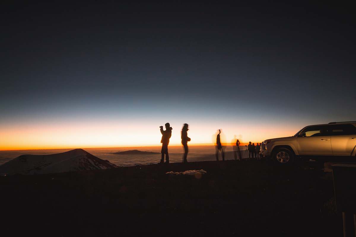 car silhouette of group of people beside SUV sunset