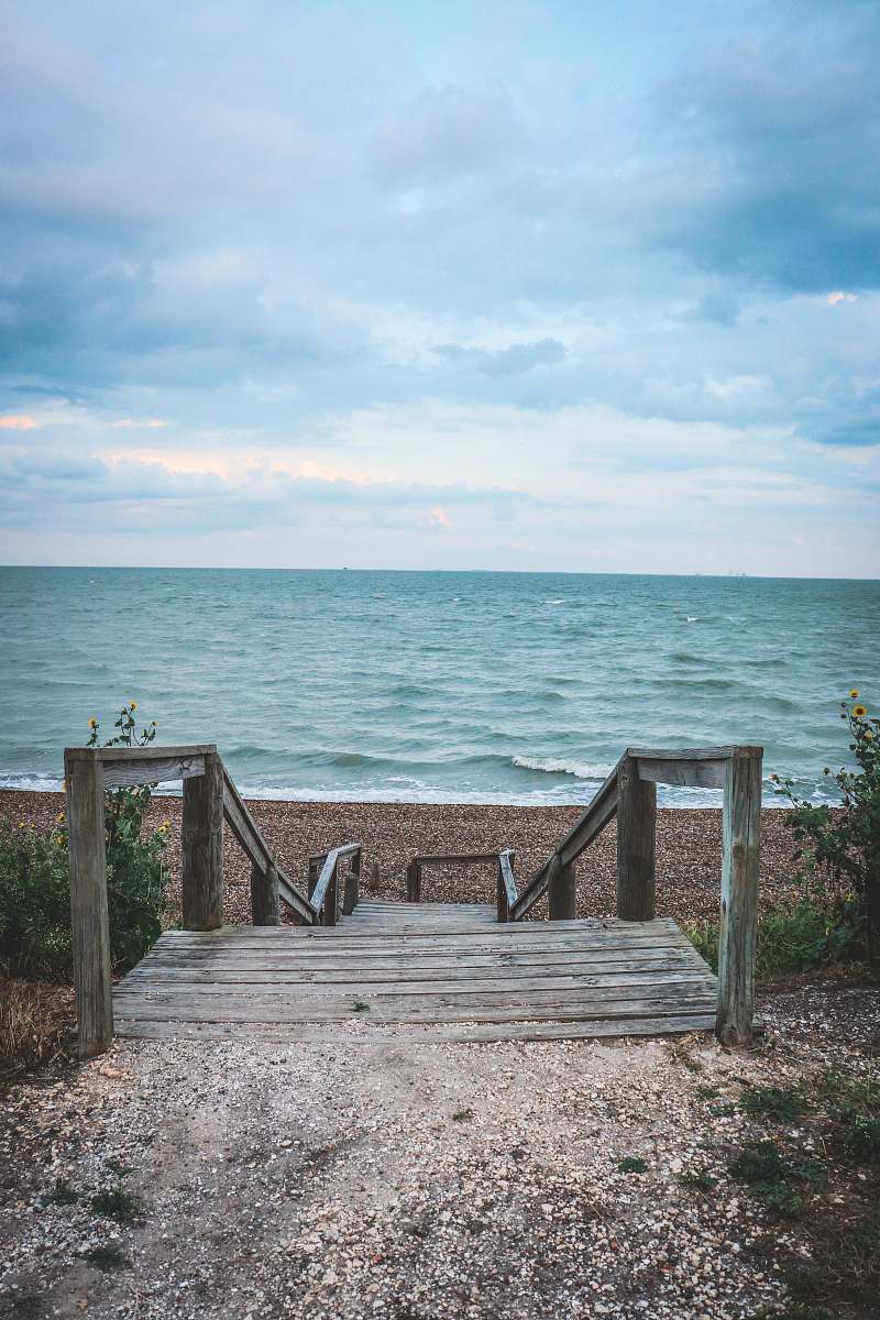 railing grey wooden stairs in front of beach boardwalk