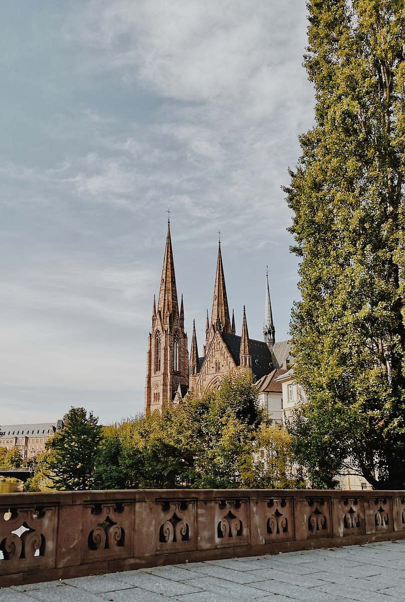 building beige concrete building with towers surrounded by trees during daytime spire