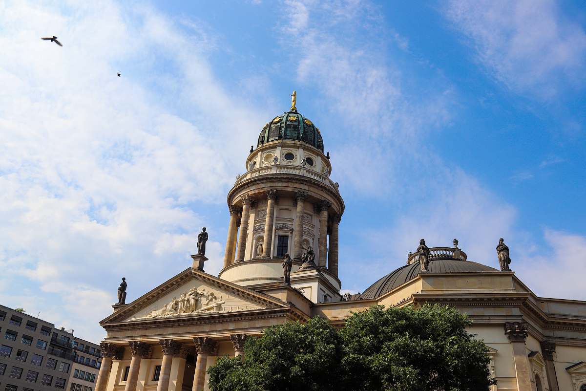 building bird flying over green and beige domed building dome