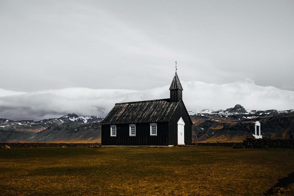 building black and white wooden house in brown field spire