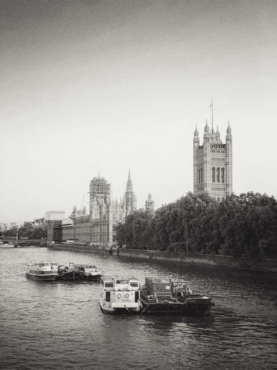 This stunning black and white photograph captures a serene daytime scene of boats sailing gracefully along the iconic Thames River. The image highlights the architectural beauty of a spire in the background, providing a striking contrast against the water's surface. Perfect for use in travel blogs, historical articles, or as a decorative piece in homes and offices, this photograph encapsulates the essence of London's rich maritime heritage.