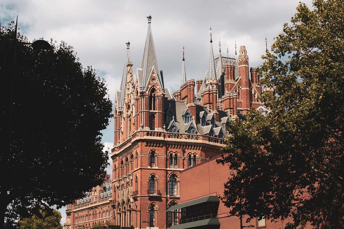 building brown and gray concrete castle near green-leafed trees spire