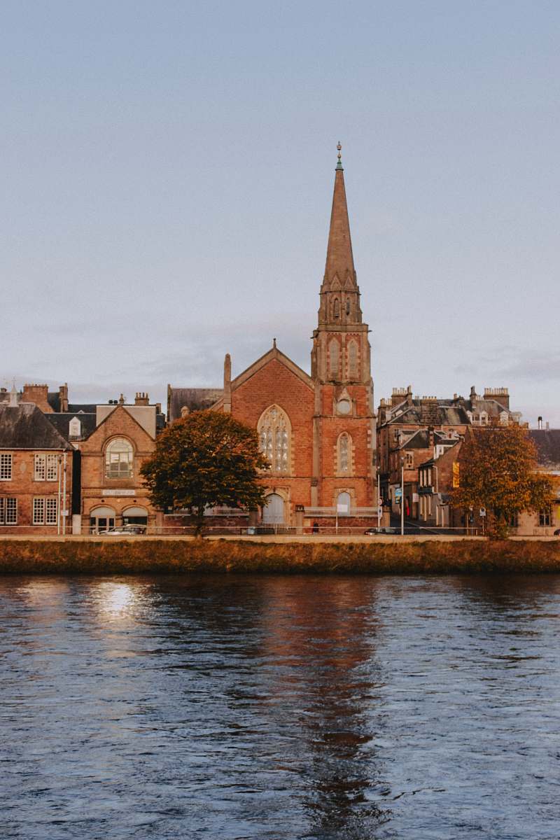 building brown concrete cathedral beside body of water spire