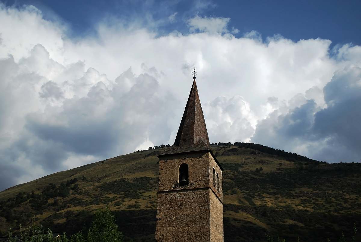 building brown tower across white clouds spire