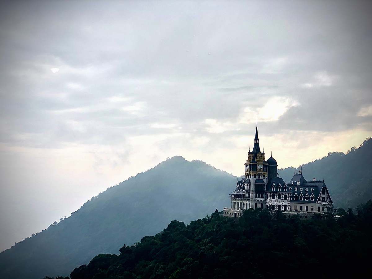 building castle on top of tree covered mountain spire