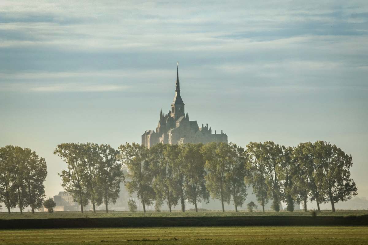 building gray castle surrounded by trees spire