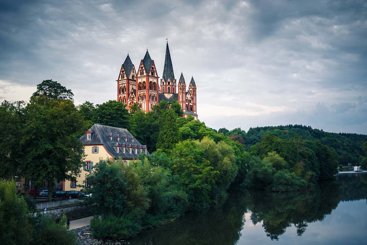 building houses surrounded by trees under clouds spire