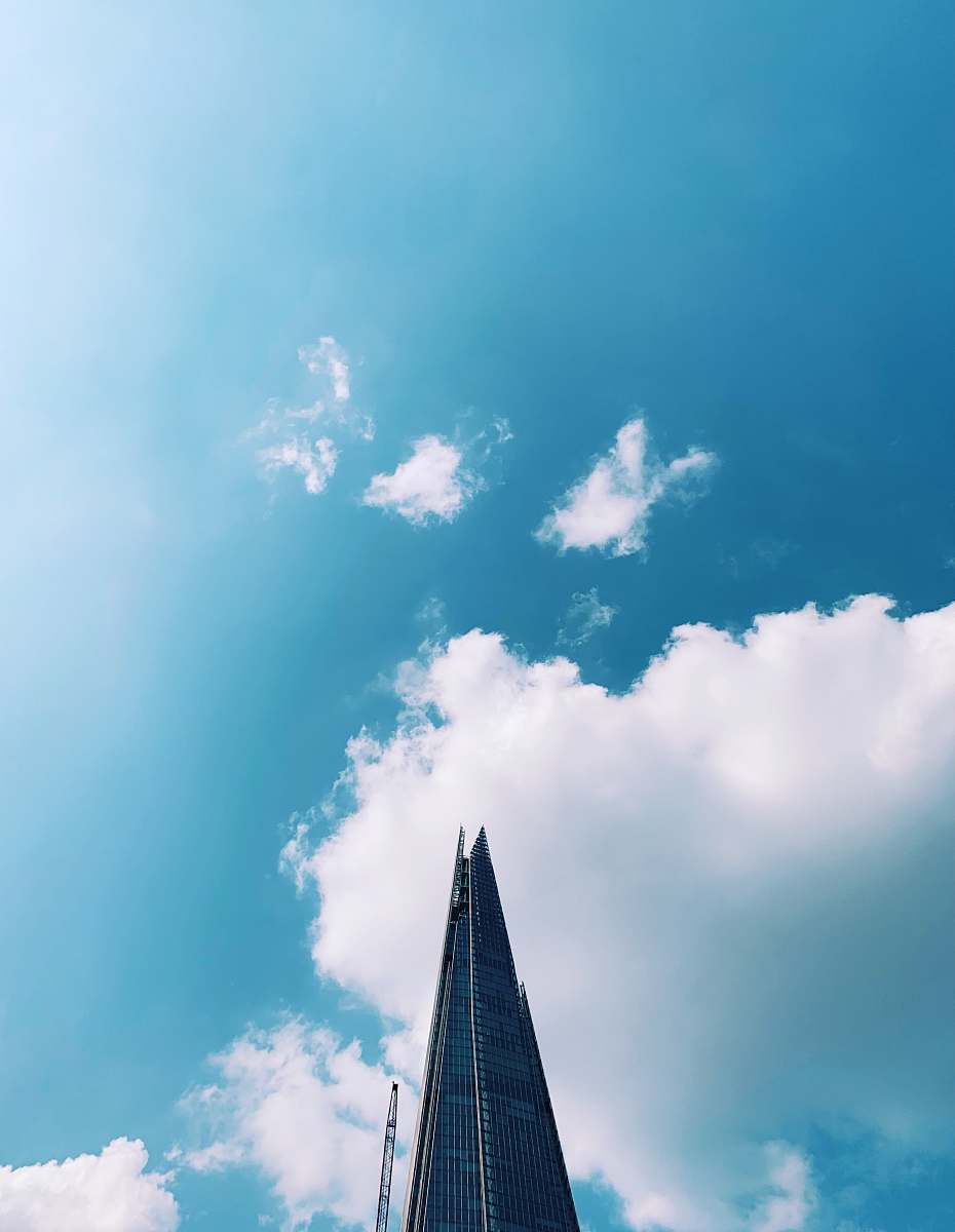 building low-angle photography of high-rise building under blue and white skies during daytime spire