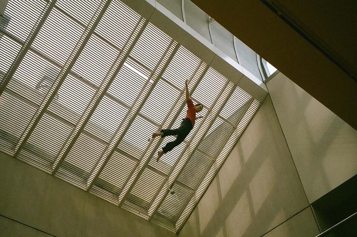 building man jumping on air at daytime window